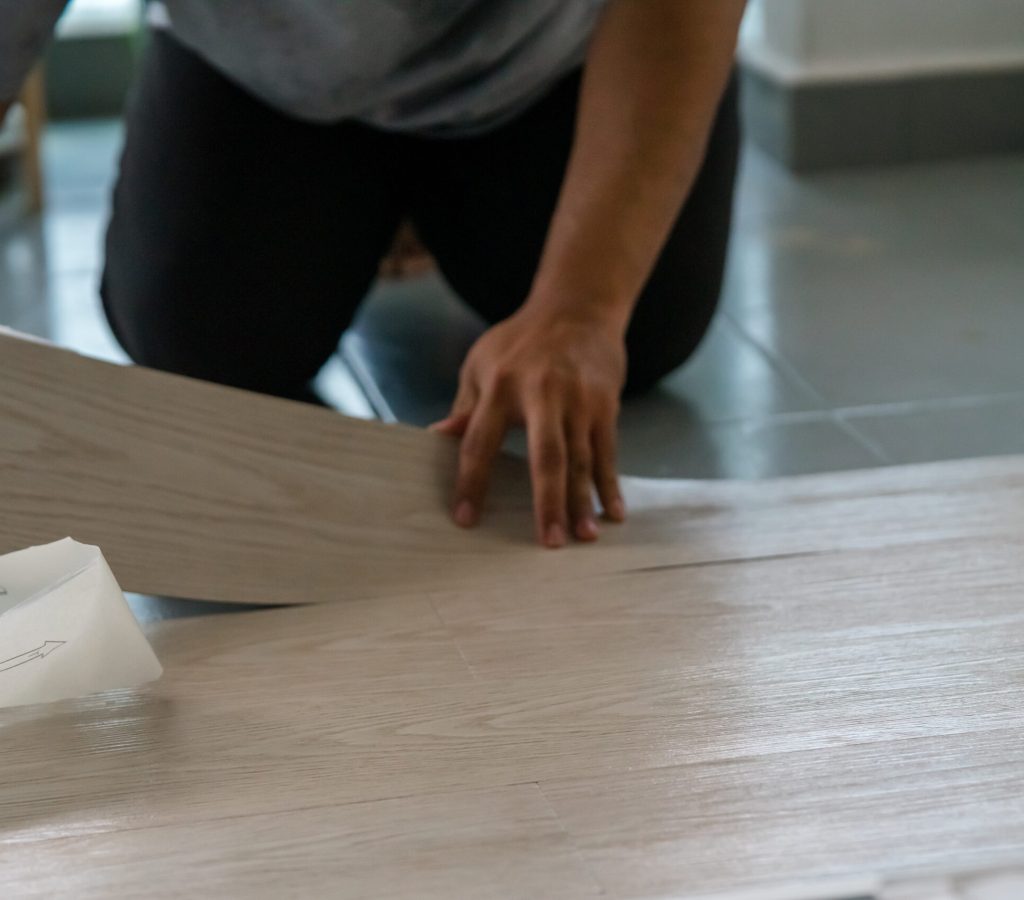 A person installing new vinyl tile floor, a DIY home project.